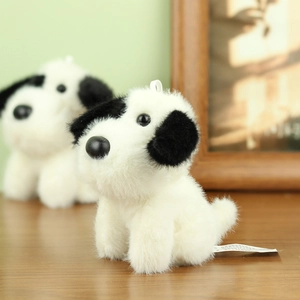 Detailed macro view of soft plush puppy keychain with black ears and white fur texture