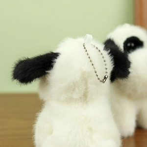 Detail of plush puppy pendant showing soft white faux fur texture and black long ears
