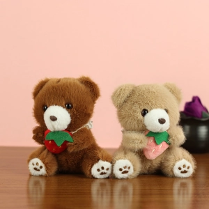 Detailed view of plush teddy bear charms featuring strawberry accessories and soft fur texture