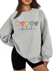 Détail d'un sweat gris avec cœurs colorés et impression 'be kind' sur tissu en maille