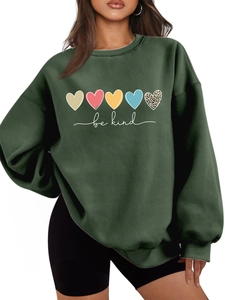 Détail d'un sweat vert forêt avec cœurs colorés et texte be kind en cursive