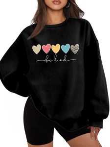 Détail de motifs cœurs colorés et inscription Be Kind sur sweat noir à col rond