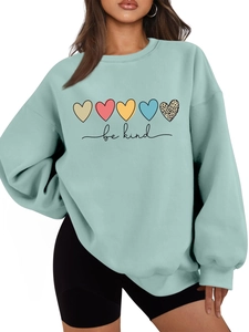 Détail d'un sweat vert menthe avec imprimés cœurs colorés et lettrage be kind