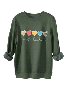 Gros plan d'un sweat-shirt vert foncé avec motifs cœurs colorés et message Be Kind