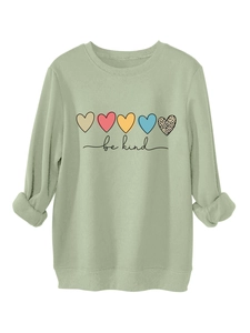 Gros plan sur l'imprimé cœur et texte 'be kind' sur un sweat-shirt vert sauge