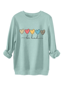 Détail des poignets côtelés du sweat vert menthe et texture imprimée 'be kind'