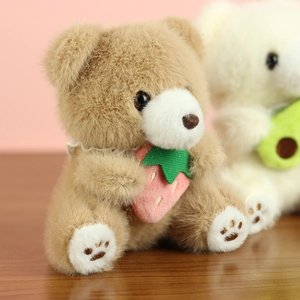 Close-up of cute plush teddy bear with lace collar and strawberry accessory on wooden desk