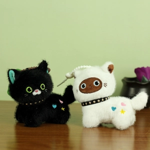Close-up of black and white plush cat pendants with colorful heart and star embroidery