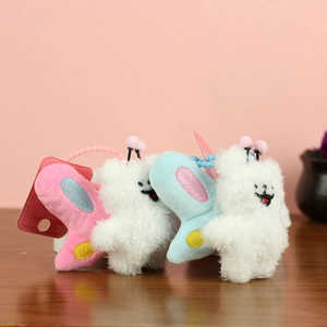 Cute plush dog charms with butterfly wings in pink and blue on a wooden table