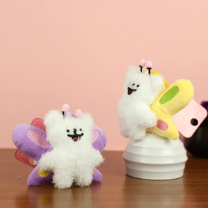 Detailed close-up of white plush bee doll charms with colorful wings and embroidery