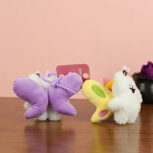 Close-up of cute plush bee puppy charms with purple plastic hooks on a wooden surface