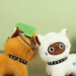 Close-up of fluffy orange and white plush cat charms with studded collars and green tag