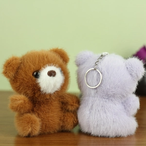 Détail de porte-clés ours en peluche marron et violet avec anneaux métalliques argentés
