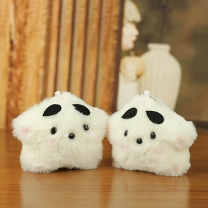 Close-up of white plush star charms with soft fur texture on a wooden surface