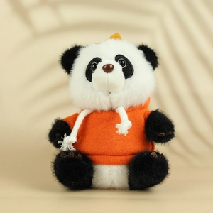 Détail de la peluche panda portant un sweat à capuche orange vif dans un décor chaleureux