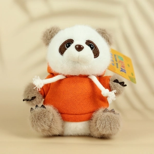 Gros plan d'une peluche panda mignonne portant un sweat à capuche orange tricoté