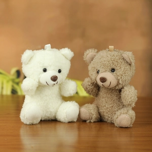 Detail view of white and brown plush teddy bear keychain charms for bags or keys
