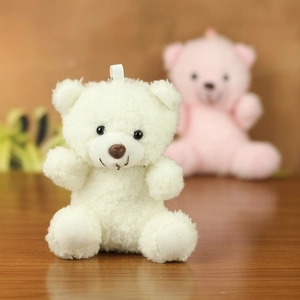 Close-up of a cream teddy bear plush keychain with curly fur and a white hanging loop