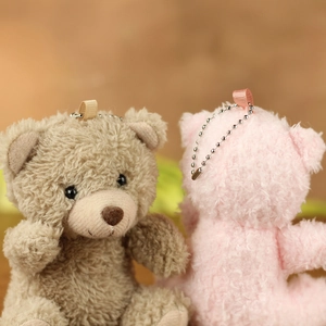 Detailed close-up of brown and pink teddy bear plush keychains with metallic bead chains