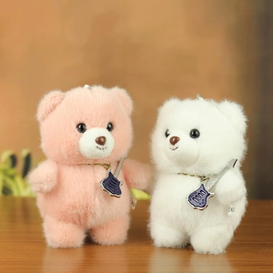 Detail of pink and white plush bears with miniature guitars on a wooden table