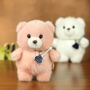 Close-up of cute plush teddy bear with guitar pendant in pink and white soft fur