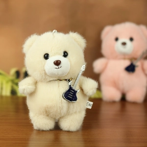 Close-up of cream teddy bear plush keychain with a mini blue electric guitar accessory