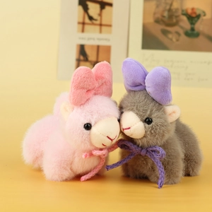 Close-up of pink and grey plush alpaca charms with soft fur and cute bow details