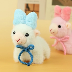Close-up of white and pink plush alpaca charms with cute bow ties and woven cords