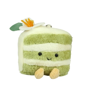 Plush matcha cake keychain with cute smile and floral detail on a white background