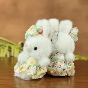 Details von niedlichen Plüschhasen-Anhängern in Blumenkleidern mit Silberketten