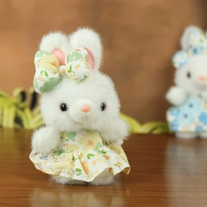 Nahaufnahme der weißen Plüschhase im Blumenkleid auf einer warmen Holzoberfläche