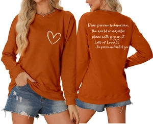 Détail d'un sweat orange brûlé avec motif cœur devant et texte inspirant au dos