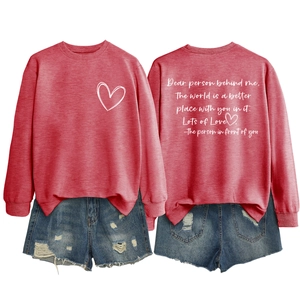 Détail du sweat rouge à col rond avec cœur blanc et texte inspirant au dos du vêtement