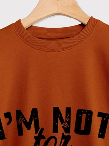 Detail of the ribbed crewneck and black I'M NOT for everyone print on a brick red sweatshirt