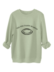 Detail of sage green sweatshirt featuring retro football graphic and 'Tis The Damn Season print