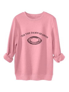Detailed macro view of pink crewneck sweatshirt with 'TIS THE DAMN SEASON lettering