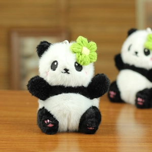 Détail d'un porte-clés peluche panda avec fleur en crochet verte et détails de rose aux joues