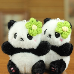 Gros plan sur des pendentifs panda en peluche avec fleur tricotée et broderie rose