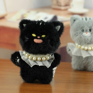 Detail van zwarte pluche kattenhanger met kanten kraag en parelketting op houten tafel