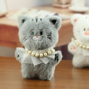 Detailopname van de grijze pluche kattenhanger met parelketting en borduurwerk op gezicht