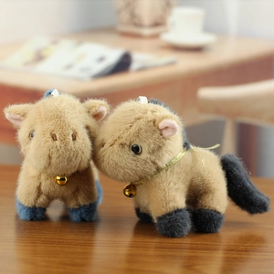 Cute brown plush pony keychain set with golden bells on a warm wooden desktop background