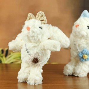 Dettaglio di un coniglietto di peluche con fiocco in maglia e borsa floreale su legno