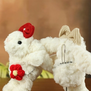 Dettaglio di ciondoli a forma di coniglio in peluche bianco con fiocchi in maglia