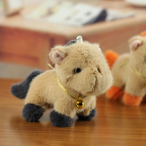 Close-up of cute plush capybara pendant with golden bell and metallic chain detail