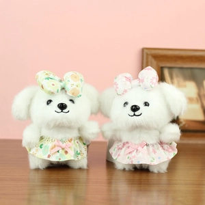 Cute white plush puppy dog dolls with floral dresses and bows on wooden table