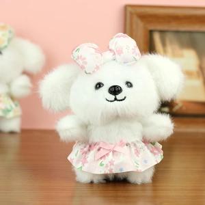 Detailed view of a plush white puppy doll wearing a pink floral dress and bow tie