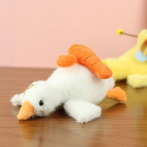 Détail d'un porte-clés oie en peluche blanche avec carotte sur une surface en bois