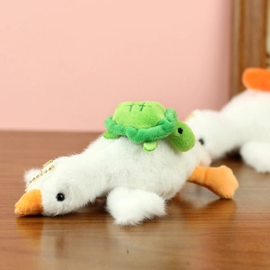 Détail d'un porte-clés oie en peluche blanche avec une tortue verte sur le dos