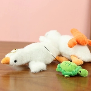 Détail de porte-clés oie blanche et tortue verte en peluche sur une table en bois