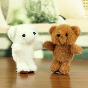 Detail von weißen und braunen Teddybär-Anhängern aus Plüsch auf einem Holztisch